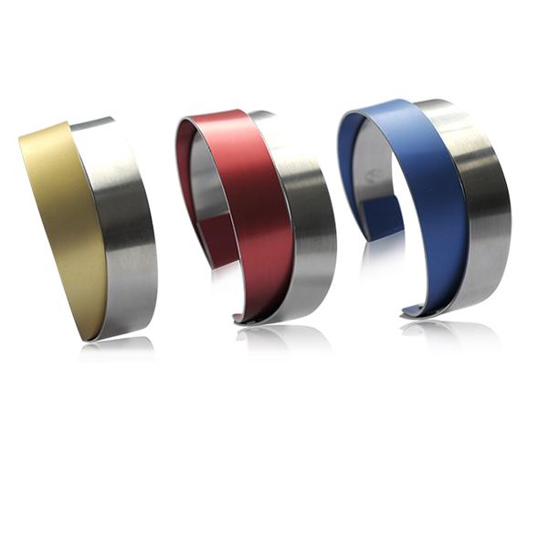 Edelstalen klem armband - De kleurenpracht van gekleurd geanodiseerd  aluminium belicht het monochrome edelstaal. Door het samengaan van contrasten wordt het sieraad autonoom, geheel aan zichzelf genoeg hebben.
